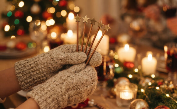 Woman wearing cozy winter mittens holding star shaped cocktail stirrers at a festive Christmas dinner party