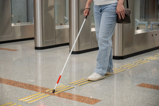 A blind woman passes through a turnstile in the subway.