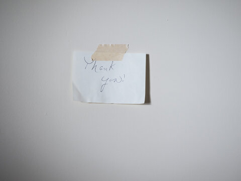 Handwritten note taped to plain wall. Simple. Quiet moment of gratitude