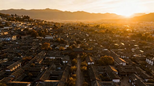 Aerial view of a densely populated town at sunset with mountains in the background