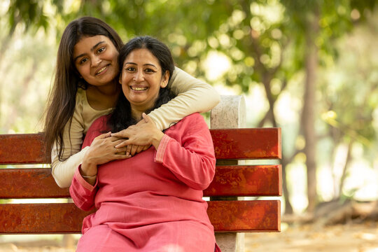 Indian Caring mother talk comfort at park. Unhappy sad young daughter suffering from psychological health problems, loving mom support make peace, hugging with depressed introvert grown up girl