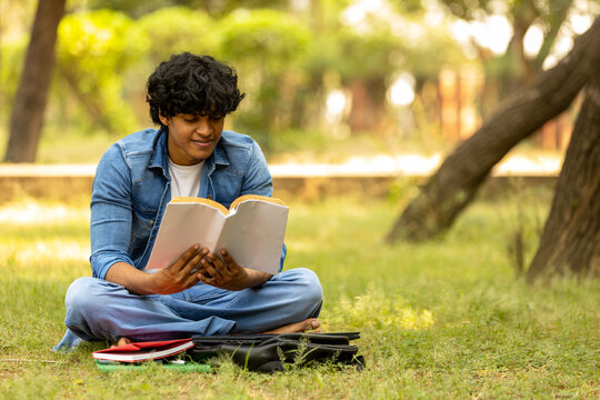 Indian male college student boy studying at park