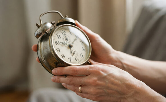 Woman holding vintage alarm clock in hands representing time management and morning wake up routine