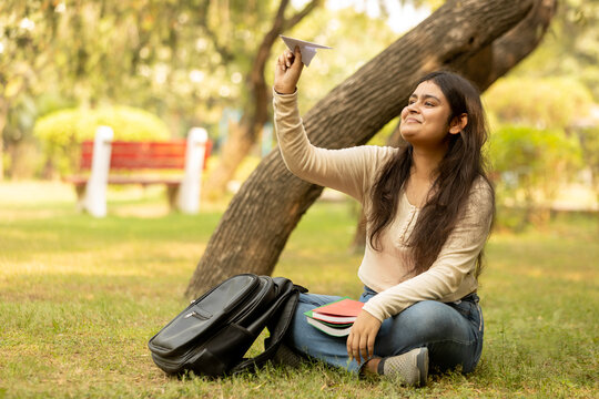 Indian college girl showing paper shape plane and happily showing various moods of air traveling and dreaming to be an air hostess. young girl. accomplishing the air hostess dream