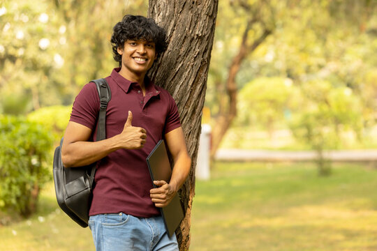 Portrait of Indian college boy showing thumbs up on the park. Asian educational student concepts