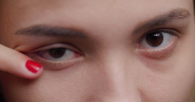 Close-up portrait of a young blonde woman with brown eyes and red nails