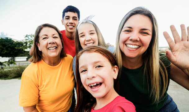 Happy multigenerational family taking selfie outdoor at city park - Grandmother, mother, teenagers and granddaughter smiling together