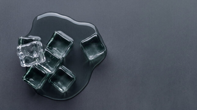 Top view of crystal clear ice cubes melting in a puddle of water on a dark textured grey background, cooling concept for summer beverages and refreshments with minimalist copy space.