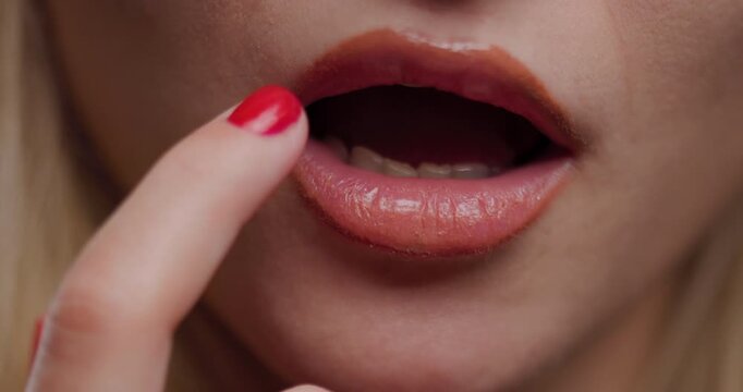 Close-up of a young blond woman touching her lips, expressing subtle emotions