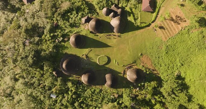 Aerial view of Waerebo Village with traditional conical houses surrounded by lush green mountains and forest in Satar Mese Barat, East Nusa Tenggara, Indonesia.