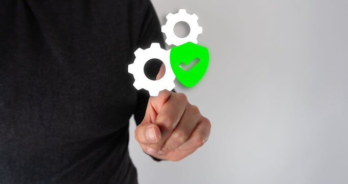 Person's hand grasps gears and shield, symbolizing security or system protection