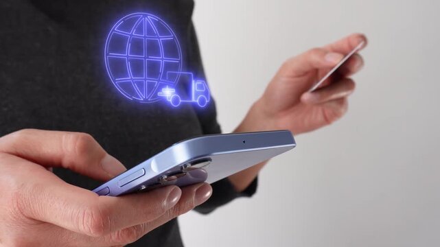 Global deliveries. Businesswoman holding a bank card and a smartphone displaying a virtual icon of a globe and a delivery truck.