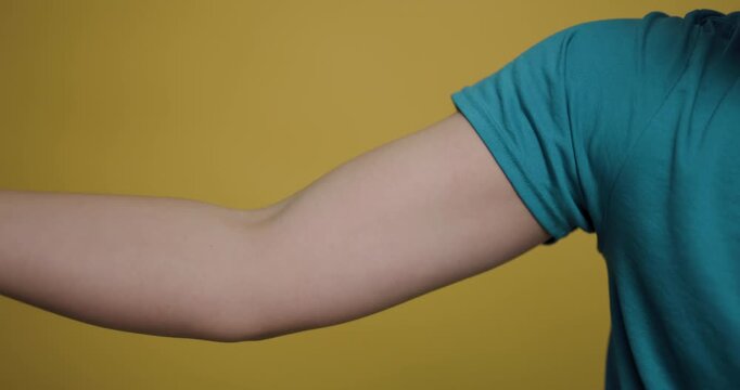 Man flexes arm muscle in casual setting with bright yellow background during a personal fitness moment