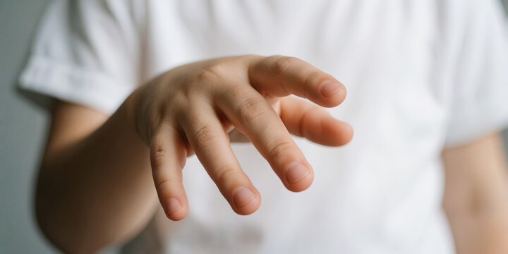 Close up of a caucasian toddler child reaching out hand forward with open fingers in white t-shirt representing curiosity and innocence