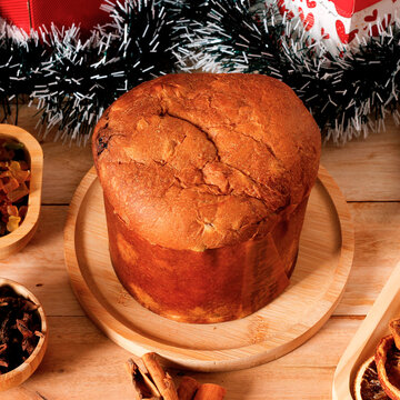 Traditional Christmas panettone filled with candied fruit and raisins, set in a festive atmosphere on a rustic wooden table.