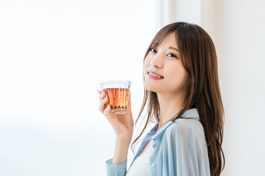 Woman Drinking Tea, Black Tea, or Barley Tea from a Glass
