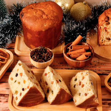 Sliced classic panettone in a Christmas setting, highlighting the soft dough, candied fruit pieces, and raisins on a decorated table.