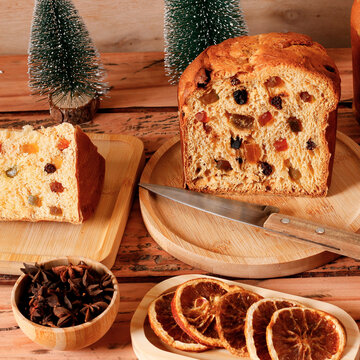 Traditional panettone with visible candied fruit and raisins, sliced on a table in a Christmas setting.