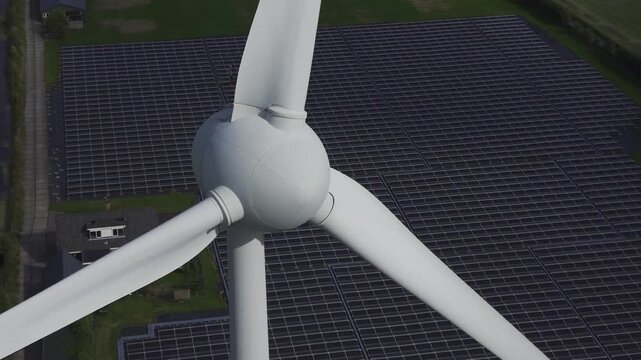 Aerial view of a wind turbine and large solar panel array in a rural landscape in 't Zand, North Holland, Netherlands.