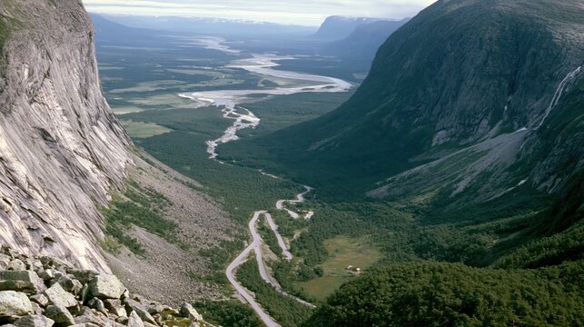 Winding mountain road through a forested valley with river