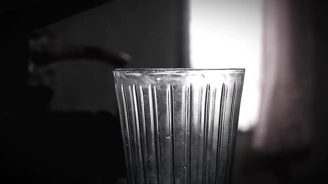 Close Up of Hand Adding Sugar to Tea with a Spoon in Glass