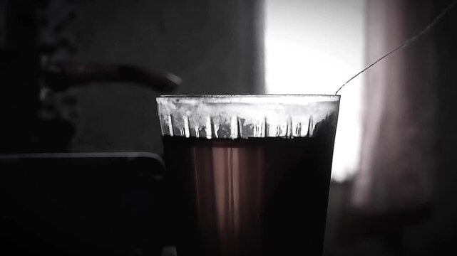 Close Up of Hand Dipping a Tea Bag into a Glass of Hot Tea