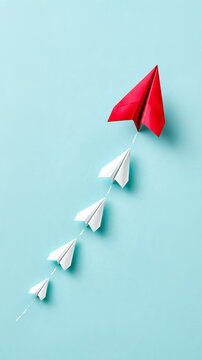 Five paper airplanes flying upwards on a blue background, with one large red plane leading four smaller white planes.