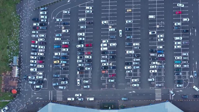 Aerial view of a large parking lot filled with numerous parked vehicles arranged in neat rows next to a building Russia.