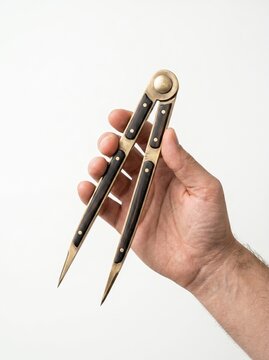 A hand holding a vintage brass and wood drafting compass on white background.