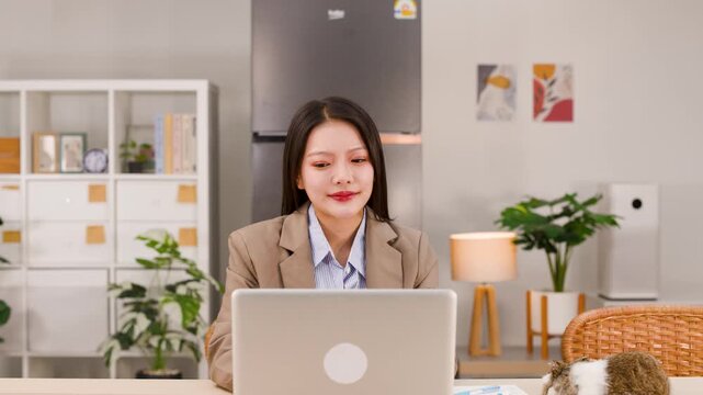 Asian Businesswoman Working on Laptop at Home Office with Pet Rabbit