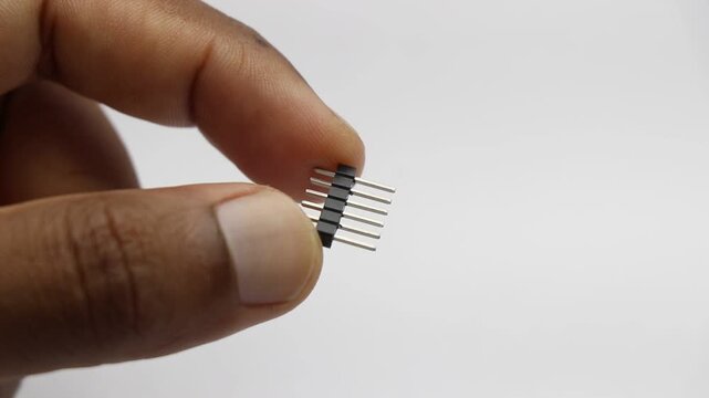 Hand holding male pin header connector strip electronic component close up shot