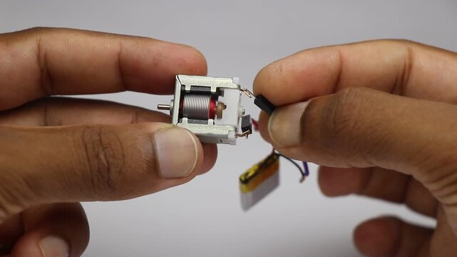 brushed dc motor with visible rotor and copper wires being tested for its working using lithium polymer battery