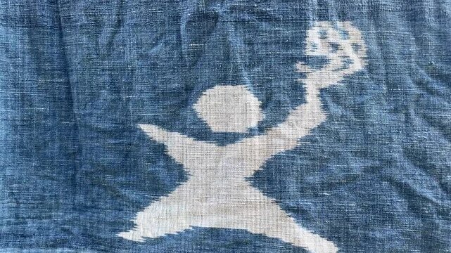 Figure on Textile: A stylized white silhouette of a figure, possibly a dancer or athlete, is depicted on a textured blue fabric, creating a graphic and artistic visual.