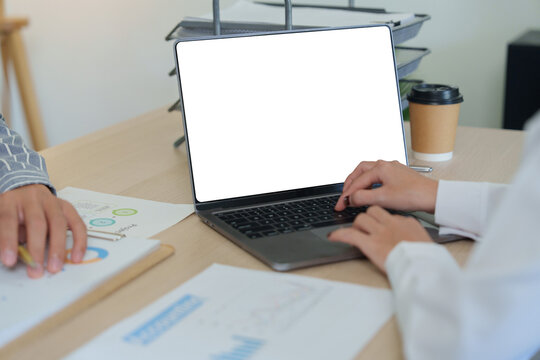 Cropped hands typing on blank laptop screen at office desk for business strategy