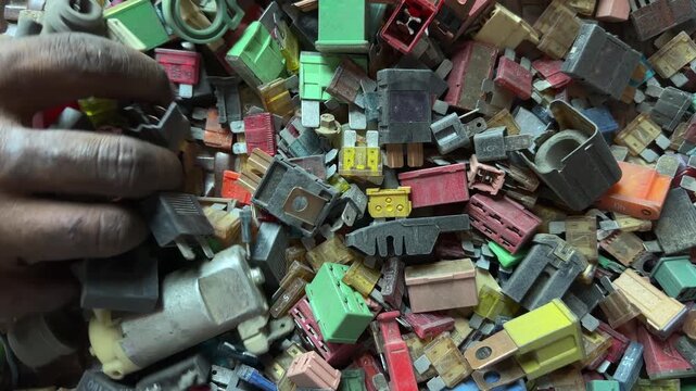 Mechanic Searching and Sorting Used Car Fuses and Electrical Components in Vehicle Repair Workshop