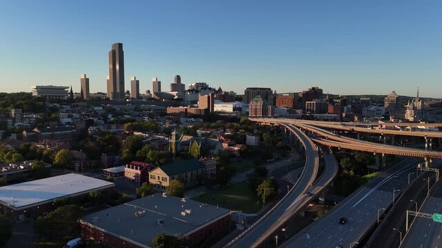 Albany New York downtown skyline and highway interchange bathed in warm golden hour sunset light 4k aerial drone video