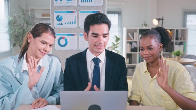 Three professional colleagues looking at a laptop screen together, discussing project details during an online video conference with a client.