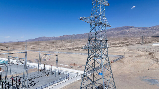 high voltage transmission tower and substation in desert landscape