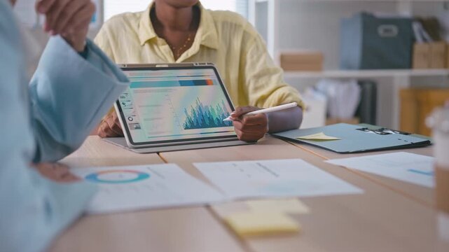 Diverse Business Team Meeting and Presenting Data Chart on Tablet, representing corporate collaboration, partnership, and teamwork.