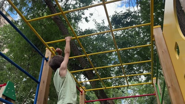 Young child climbing and playing on monkey bars at an outdoor playground. Active childhood, outdoor recreation, exercise and physical activity. 