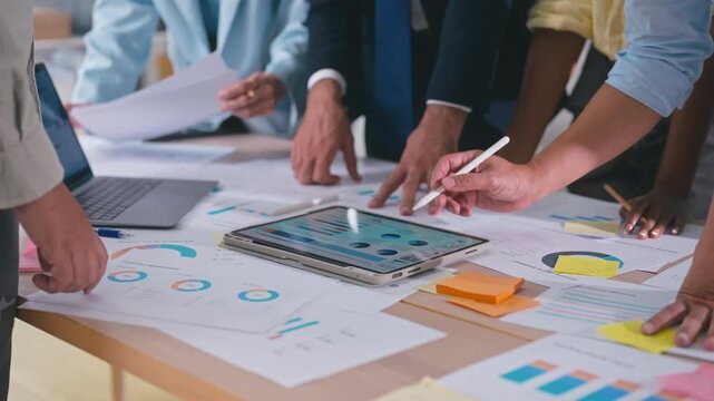 Business team discussing financial charts and data on a digital tablet during a meeting in a modern office corporate strategy, and teamwork.
