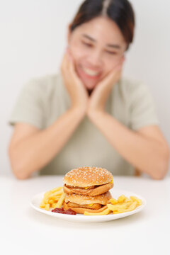 happy woman eating Juicy beef burger with melted cheddar cheese, potato chips. Unhealthy, High calorie, Fast food craving, Obesity, diet, weight loss, junk food and lifestyle