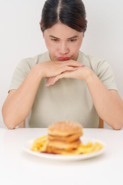 Unhappy woman disgust gesture and Bored to eat Juicy beef burger and potato chips. Unhealthy, High calorie, Fast food craving, Obesity, diet, weight loss and junk food