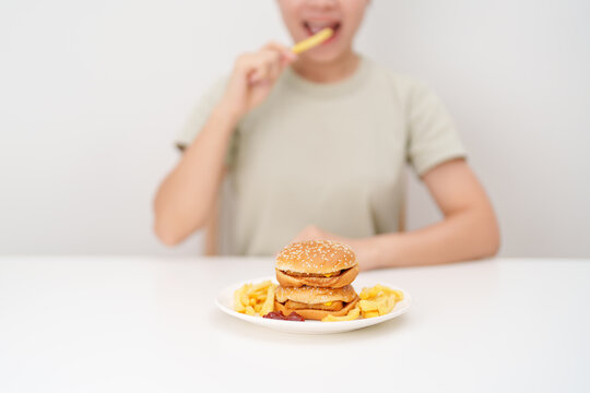 happy woman eating Juicy beef burger with melted cheddar cheese, potato chips. Unhealthy, High calorie, Fast food craving, Obesity, diet, weight loss, junk food and lifestyle