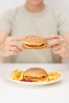 happy woman eating Juicy beef burger with melted cheddar cheese, potato chips. Unhealthy, High calorie, Fast food craving, Obesity, diet, weight loss, junk food and lifestyle