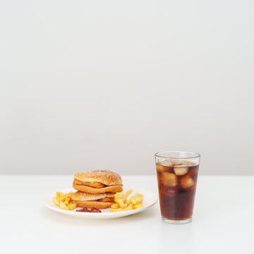 juicy beef burger with melted cheddar cheese, potato chips and carbonated Soft drinks on table. Unhealthy, High calorie, Fast food craving, Obesity, diet, weight loss, junk food and lifestyle