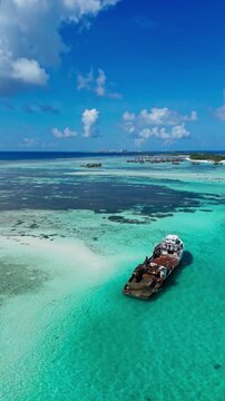 High angle aerial shot of rusting shipwreck disaster on tropical coral reef. Concept of pollution, marine decay, history, climate change, and maritime environmental impact.Vertical video