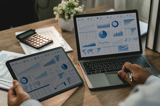 Businessman analyzing financial data on laptop and tablet dashboards, reviewing charts, graphs and performance metrics for business finance reporting and data analysis.