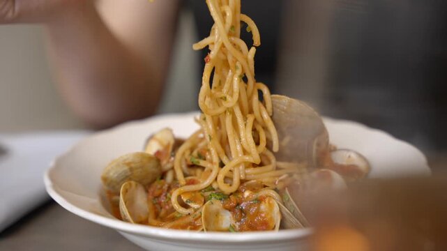 A fork lifts strands of seafood spaghetti from a plated pasta dish, capturing the movement of the noodles and the presentation of the meal. Footage highlighting Italian cuisine, seafood and freshly se