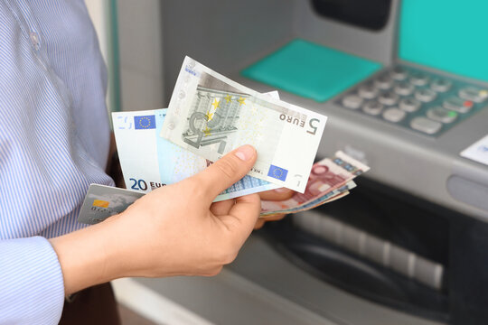 Personal finance and banking, person withdrawing cash from an atm with euro banknotes and a credit card for financial management and savings